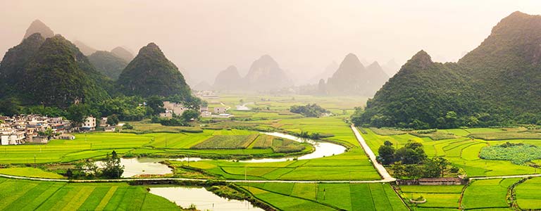 A Chinese village surrounded by green mountains and rice fields